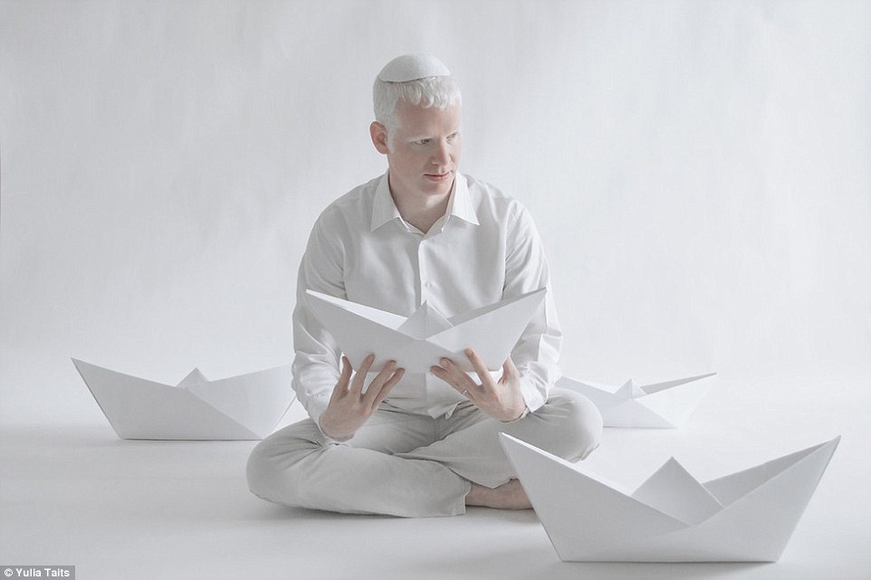 Jewish model Eydan holds a white paper arrangement as he poses cross-legged for Yulia Tait